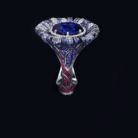 Крупное кольцо своими очертаниями напоминает распустившийся бутон, внутри которого скрывалось настоящее сокровище – крупный синий сапфир в тонком бриллиантовом обрамлении. Россыпь мелких сапфиров и бриллиантов на лепестках подчеркивает глубину цвета.