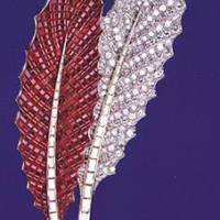 В броши в форме двух листьев остролиста поражает сочетание прозрачных бриллиантов и насыщенного цвета рубинов. Кстати, техника невидимой оправы впервые была применена именно в этом украшении.